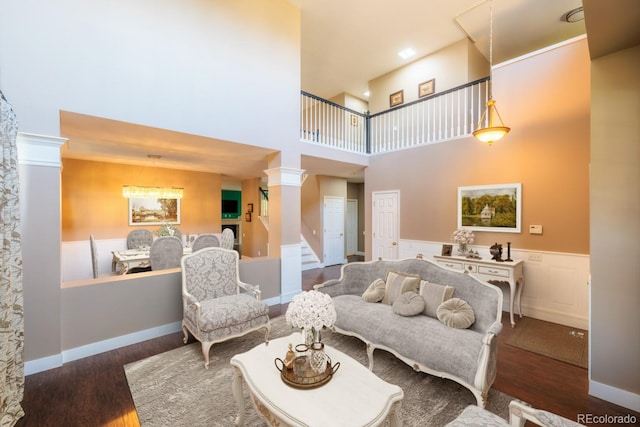 living room featuring decorative columns, a high ceiling, and dark hardwood / wood-style flooring