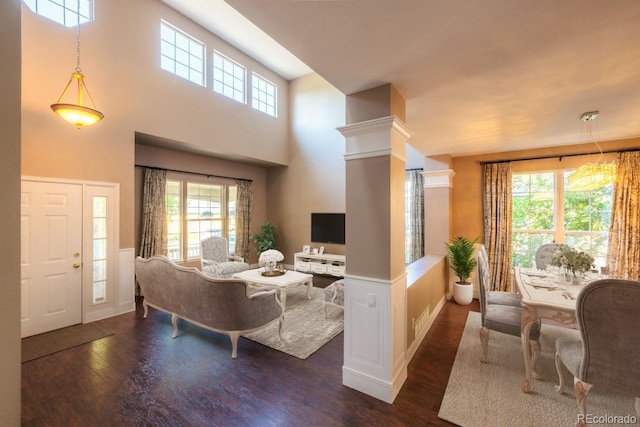 living room with decorative columns, plenty of natural light, a high ceiling, and dark hardwood / wood-style flooring