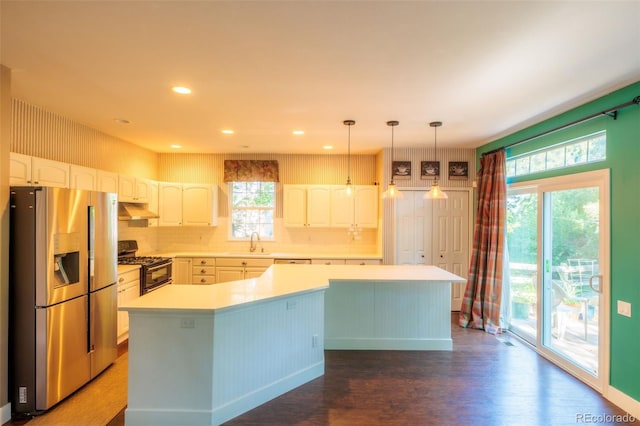 kitchen featuring gas stove, stainless steel fridge with ice dispenser, hanging light fixtures, a kitchen island, and white cabinets