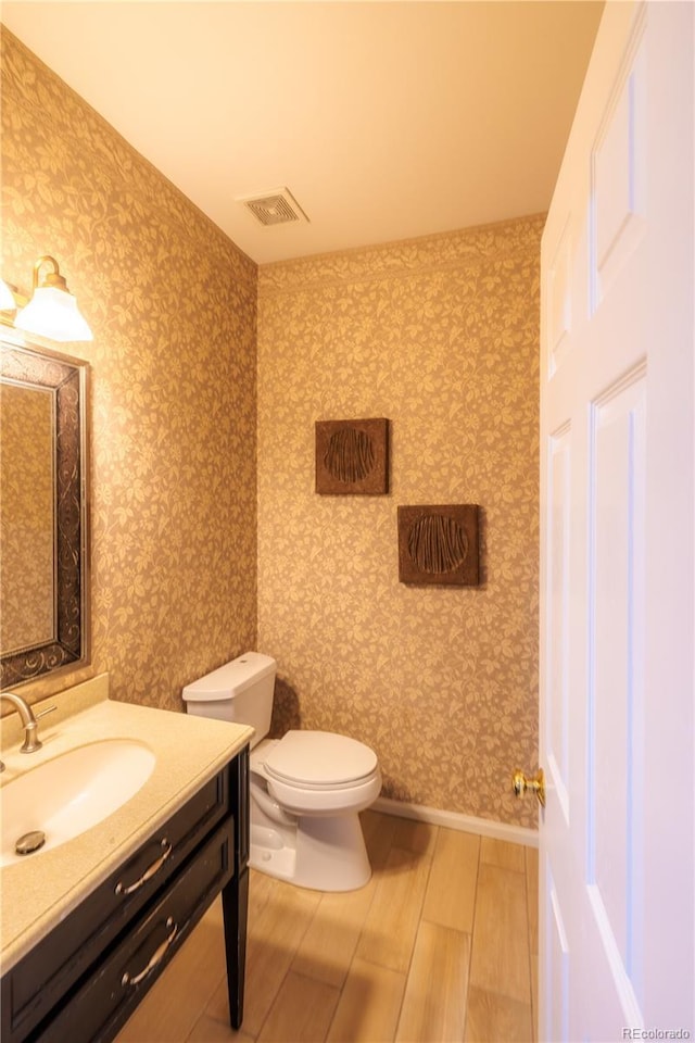 bathroom featuring vanity, wood-type flooring, and toilet