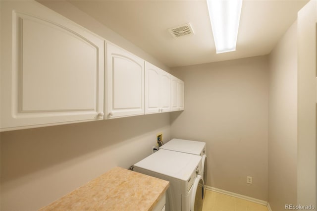 washroom with cabinets and washing machine and clothes dryer