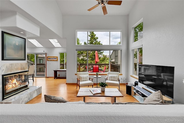 766 Chimney Creek Dr, Golden, CO 80401 - living room with a high ceiling, a tile fireplace, a skylight, light wood finished floors, and a ceiling fan