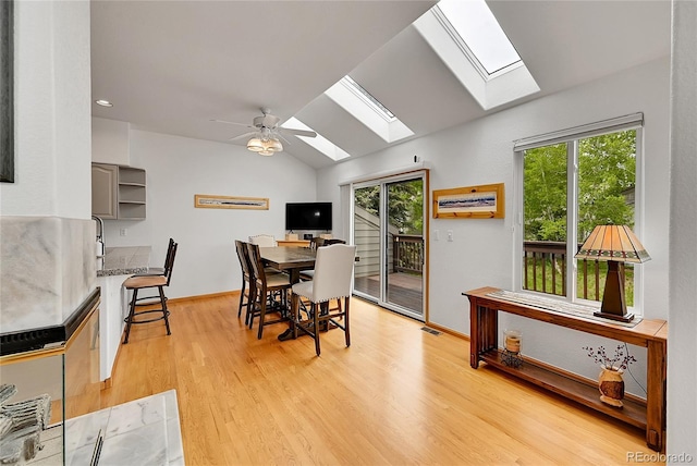 766 Chimney Creek Dr, Golden, CO 80401 - dining room with a skylight, vaulted ceiling, light wood-style flooring, a ceiling fan, and baseboards