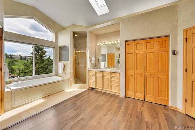 766 Chimney Creek Dr, Golden, CO 80401 - bathroom featuring a skylight, a stall shower, wood finished floors, vanity, and a bath