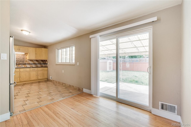 3216 Revere St, Aurora, CO 80011 - kitchen with light brown cabinetry, light wood-style flooring, freestanding refrigerator, backsplash, and baseboards