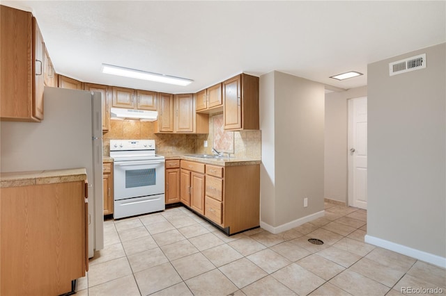 3216 Revere St, Aurora, CO 80011 - kitchen featuring white appliances, under cabinet range hood, light tile patterned floors, tasteful backsplash, and light countertops