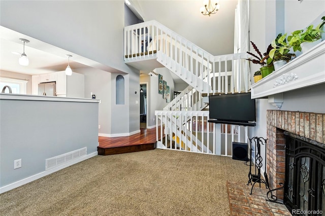 13651 W 65th Ave, Arvada, CO 80004 - carpeted living area featuring stairs, a high ceiling, and a brick fireplace