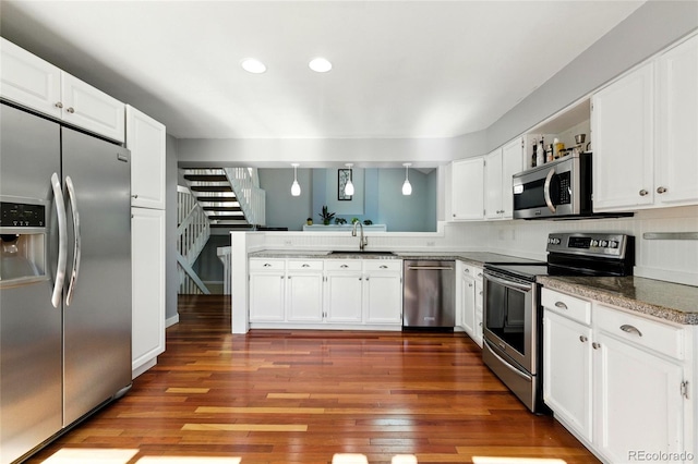 13651 W 65th Ave, Arvada, CO 80004 - kitchen with appliances with stainless steel finishes, wood finished floors, white cabinetry, recessed lighting, and a peninsula