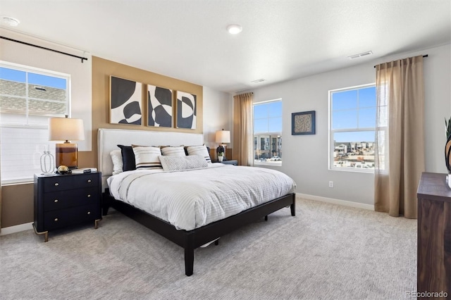 bedroom with baseboards, visible vents, and light colored carpet