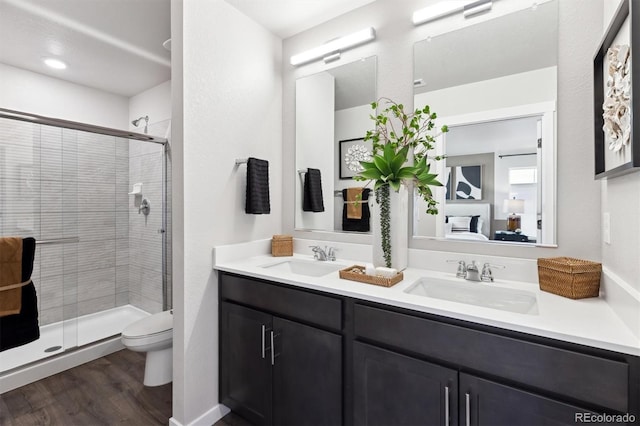 ensuite bathroom with a sink, toilet, connected bathroom, and wood finished floors