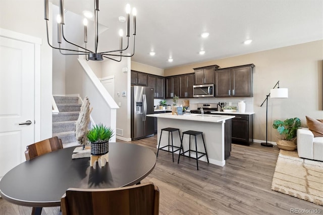 dining space featuring recessed lighting, a notable chandelier, baseboards, stairs, and light wood-style floors