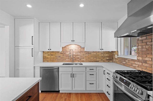 kitchen with extractor fan, appliances with stainless steel finishes, a sink, light countertops, and recessed lighting