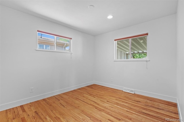 empty room with baseboards, healthy amount of natural light, light wood finished floors, and recessed lighting