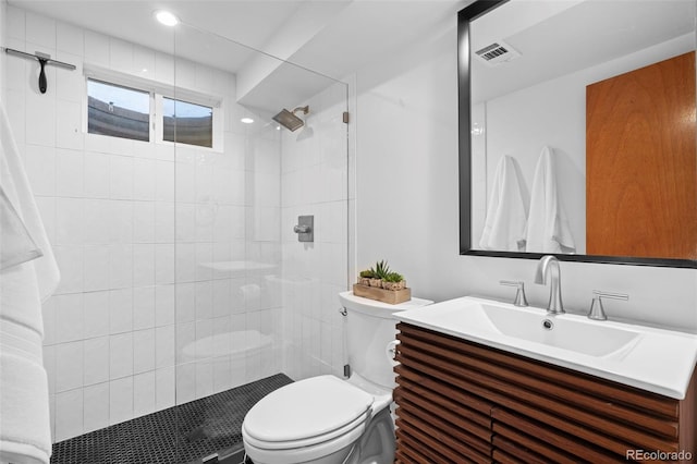 bathroom featuring toilet, a tile shower, and vanity