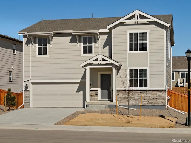 view of front of home with a shingled roof, concrete driveway, an attached garage, fence, and stone siding