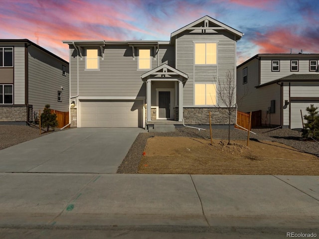 view of front facade with a garage, stone siding, driveway, and fence