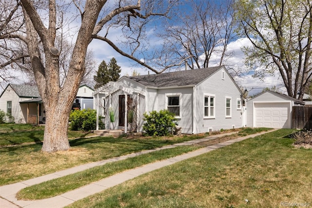 view of front of home with a front lawn, an outbuilding, roof with shingles, and a garage