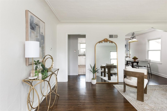 hall featuring dark wood-style floors, arched walkways, crown molding, and visible vents
