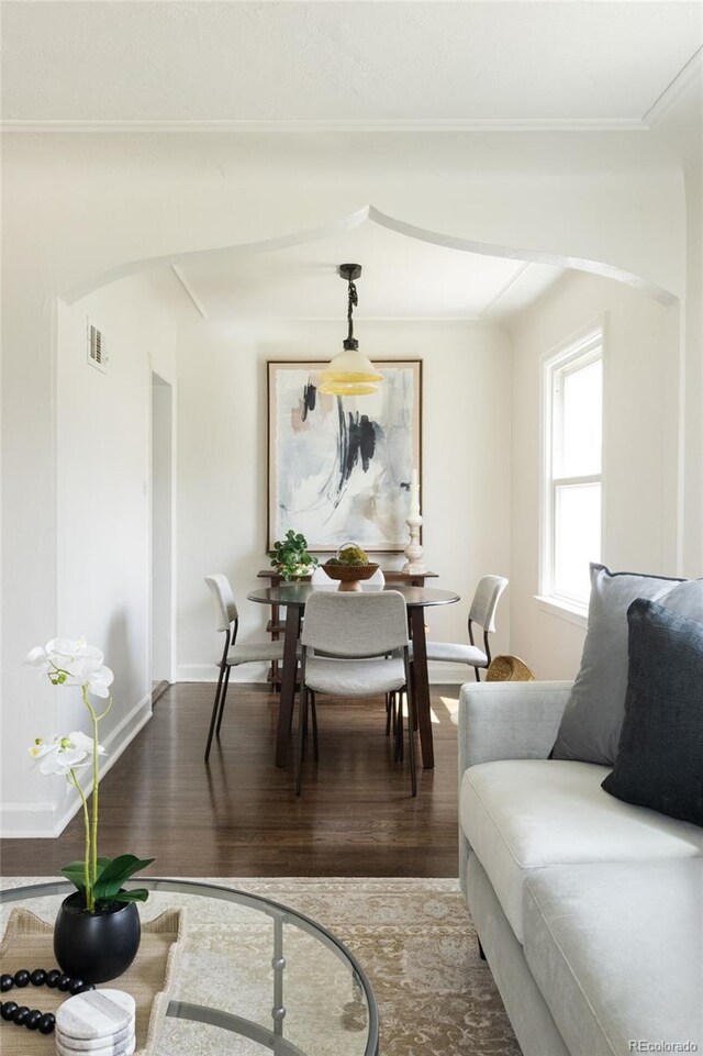 dining area featuring baseboards, wood finished floors, visible vents, and arched walkways