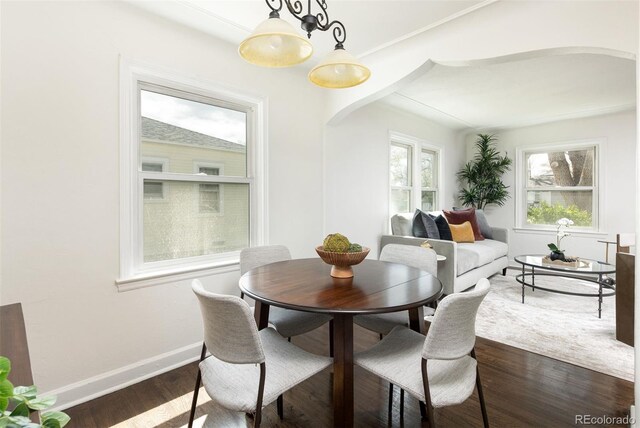 dining space featuring baseboards, dark wood-style floors, and arched walkways