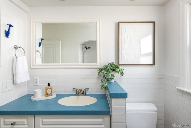 bathroom with tile walls, vanity, and toilet
