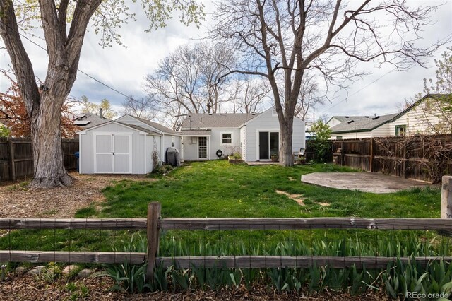 back of house with a lawn, a fenced backyard, a storage unit, and an outbuilding