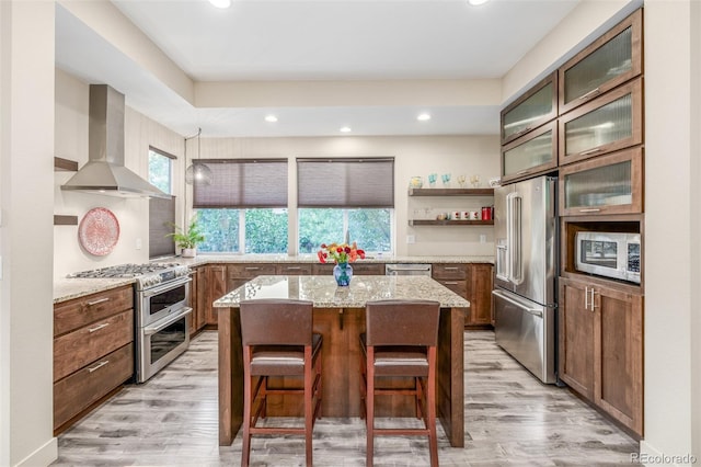6761 Alan Dr, Denver, CO 80221 - kitchen featuring stainless steel appliances, wall chimney range hood, a center island, light stone countertops, and light wood-type flooring