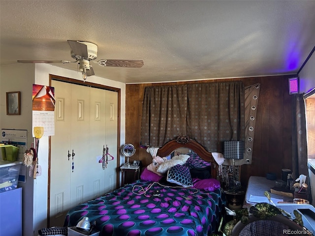 bedroom featuring wood walls, carpet flooring, ceiling fan, a textured ceiling, and a closet