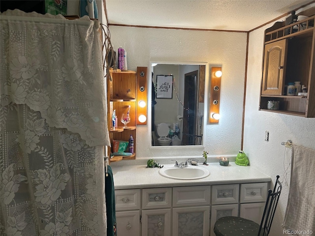 bathroom with ornamental molding, vanity, toilet, and a textured ceiling