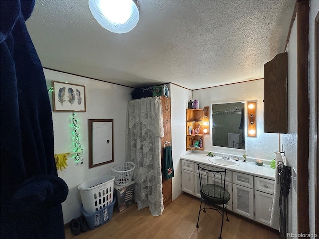 bathroom featuring vanity, electric panel, hardwood / wood-style floors, and a textured ceiling