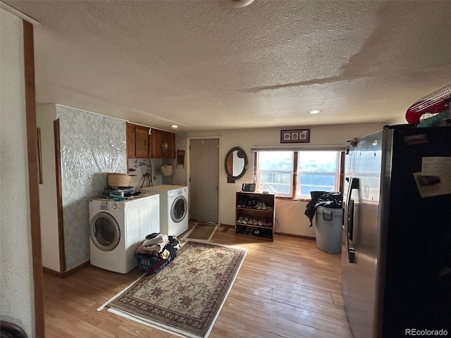 laundry area with washer and clothes dryer, a textured ceiling, and light wood-type flooring