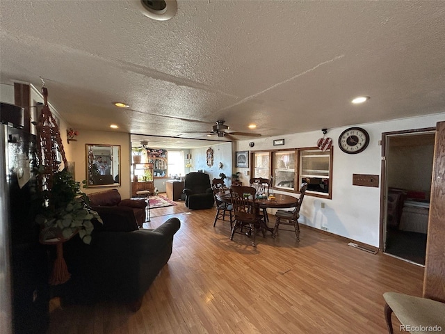 dining space with hardwood / wood-style flooring, ceiling fan, and a textured ceiling