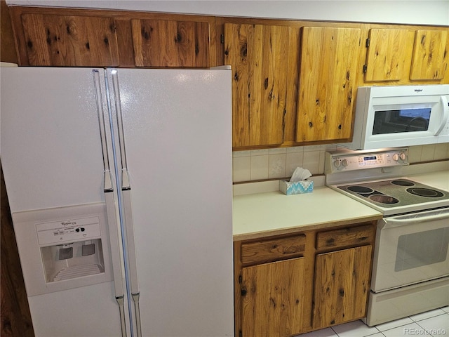 kitchen featuring light tile patterned floors, white appliances, and tasteful backsplash