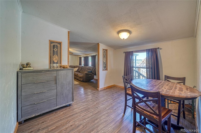 dining space with a textured ceiling, crown molding, and hardwood / wood-style flooring