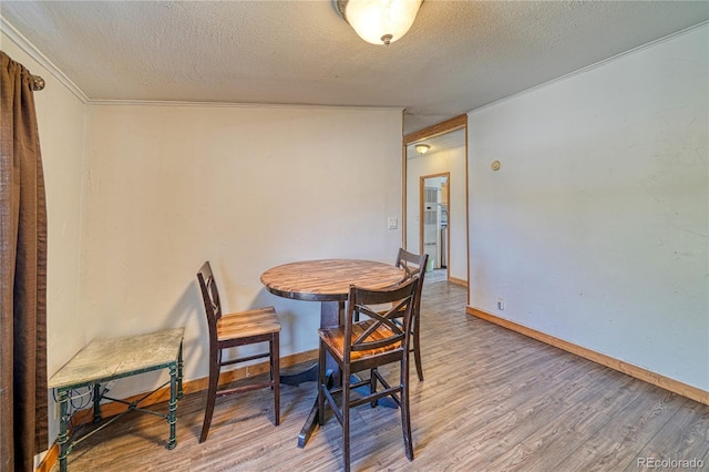 dining area with a textured ceiling, wood-type flooring, and crown molding