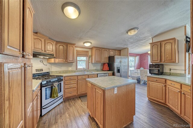 205 Sabeta Ave, Poncha Springs, CO 81242 - kitchen featuring appliances with stainless steel finishes, under cabinet range hood, a textured ceiling, a kitchen island, and plenty of natural light