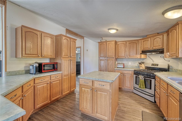 kitchen featuring lofted ceiling, a textured ceiling, stainless steel appliances, a center island, and light hardwood / wood-style floors