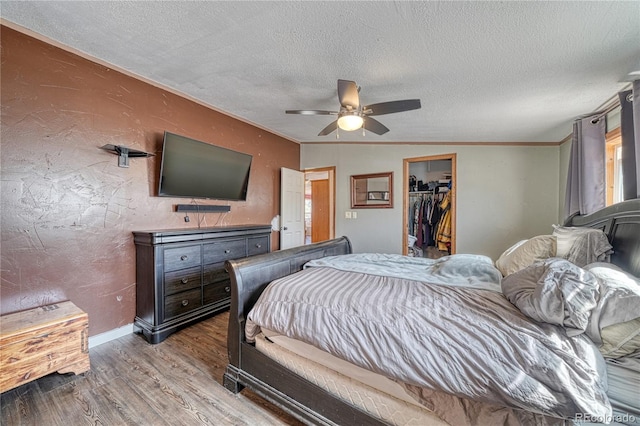 bedroom featuring ceiling fan, lofted ceiling, a textured ceiling, a spacious closet, and light wood-type flooring