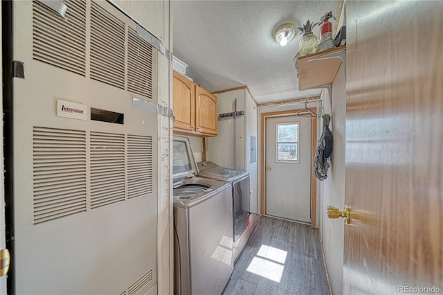 laundry room featuring heating unit, a textured ceiling, cabinets, hardwood / wood-style flooring, and separate washer and dryer