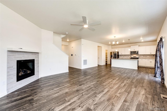 13376 Willow St, Thornton, CO 80602 - unfurnished living room with ceiling fan, dark wood-style floors, a chandelier, and a tile fireplace