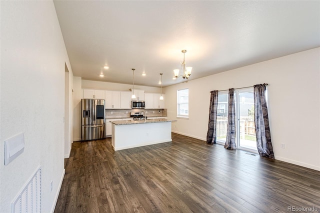 13376 Willow St, Thornton, CO 80602 - kitchen with appliances with stainless steel finishes, a chandelier, white cabinetry, a center island with sink, and dark wood-type flooring