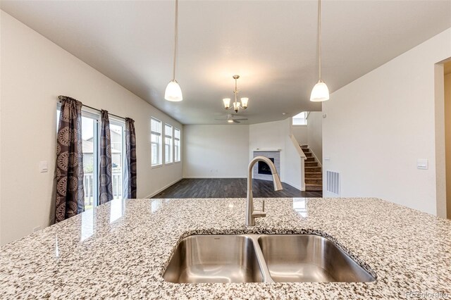 13376 Willow St, Thornton, CO 80602 - kitchen featuring light stone counters, wood finished floors, pendant lighting, a chandelier, and open floor plan