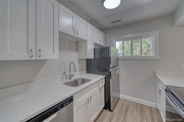 kitchen with light wood-type flooring, stainless steel appliances, white cabinetry, and sink