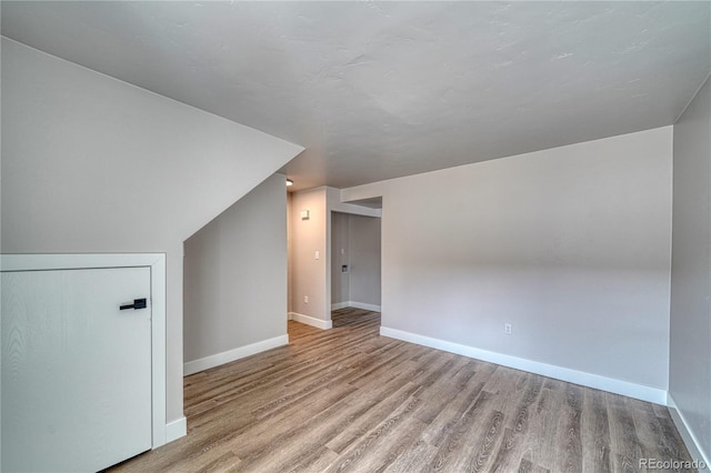 additional living space with light hardwood / wood-style floors and vaulted ceiling