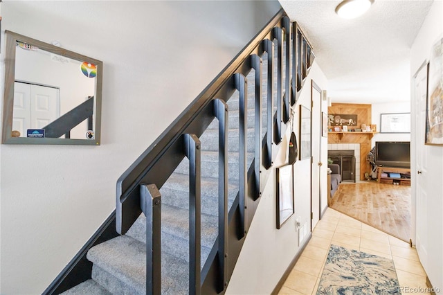 stairs featuring a large fireplace, a textured ceiling, and tile patterned flooring