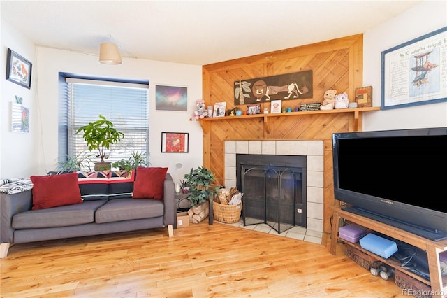 living room featuring hardwood / wood-style flooring, wood walls, and a tile fireplace