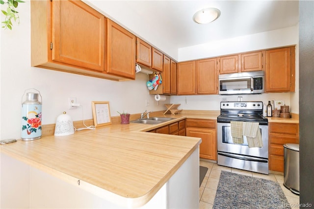 kitchen with light tile patterned floors, stainless steel appliances, kitchen peninsula, and sink