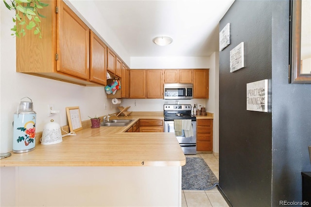 kitchen with sink, appliances with stainless steel finishes, kitchen peninsula, and light tile patterned flooring