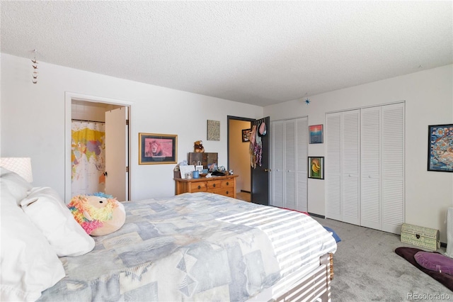 carpeted bedroom featuring two closets and a textured ceiling