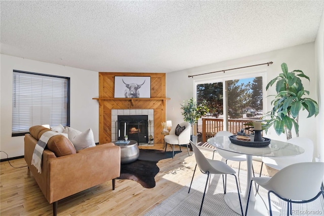 living room featuring light wood-style floors, a fireplace, and a textured ceiling